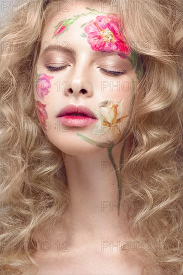 Beautiful blond girl with tresses and a floral pattern on the face. Beauty flowers. Portrait shot in studio