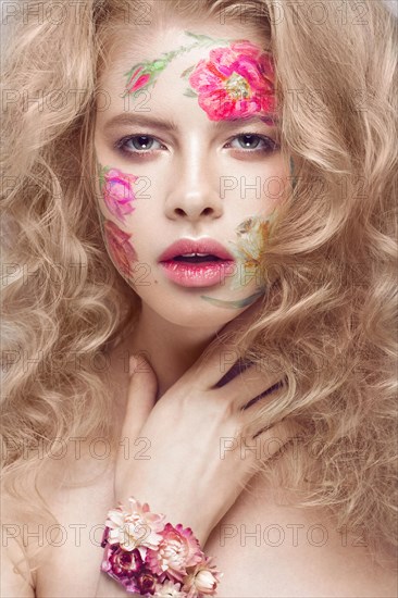 Beautiful blond girl with tresses and a floral pattern on the face. Beauty flowers. Portrait shot in studio