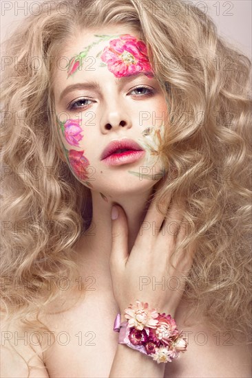 Beautiful blond girl with tresses and a floral pattern on the face. Beauty flowers. Portrait shot in studio