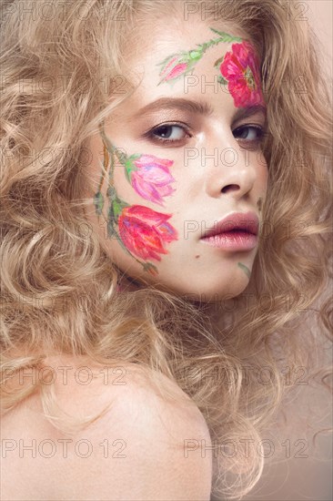 Beautiful blond girl with tresses and a floral pattern on the face. Beauty flowers. Portrait shot in studio