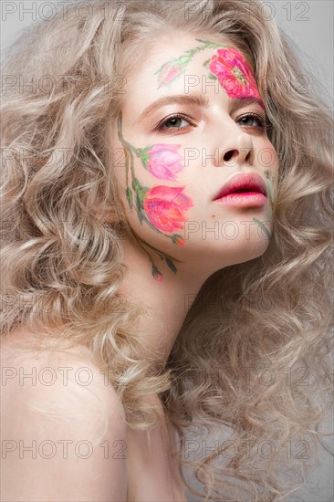 Beautiful blond girl with tresses and a floral pattern on the face. Beauty flowers. Portrait shot in studio