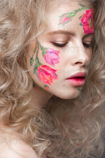 Beautiful blond girl with tresses and a floral pattern on the face. Beauty flowers. Portrait shot in studio