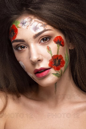 Beautiful brunette girl with curls and a floral pattern on the face. Beauty flowers. Portrait shot in studio