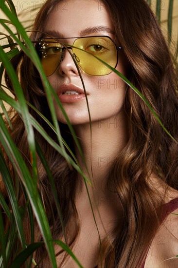 Beautiful sexy woman in a bikini posing in the middle of green plants. Summer look. Beauty face. Photo taken in the studio