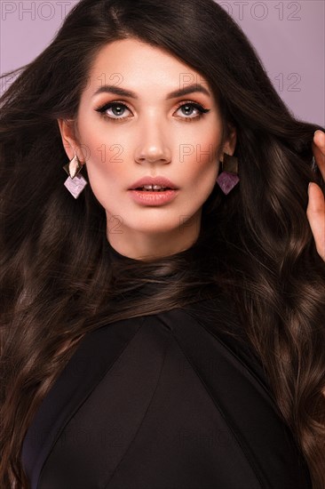 Beautiful brunette woman with curls and classic make-up in a black dress. Beauty face. Photo taken in studio