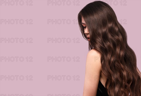 Beautiful brunette woman with curls and classic make-up in a black dress. Beauty face. Photo taken in studio