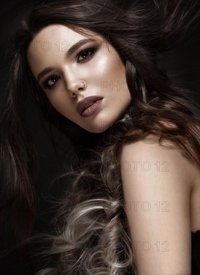 Brunette girl with a creative hairstyle braids and dark make-up. Beauty face. Photo taken in the studio