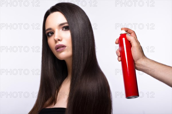 Beautiful brunette model with classic makeup and bottle of hair products. beauty face. Portrait shot in the studio