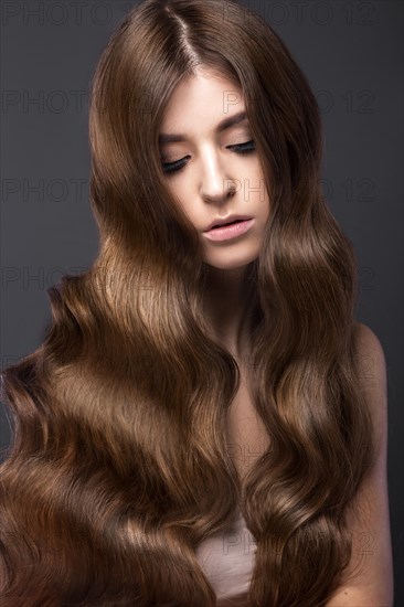 Beautiful brunette girl with a perfectly curls hair and classic make-up. Beauty face. Picture taken in the studio
