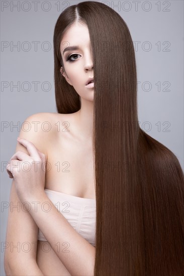 Beautiful brunette girl with a perfectly smooth hair and classic make-up. Beauty face. Picture taken in the studio on a white background