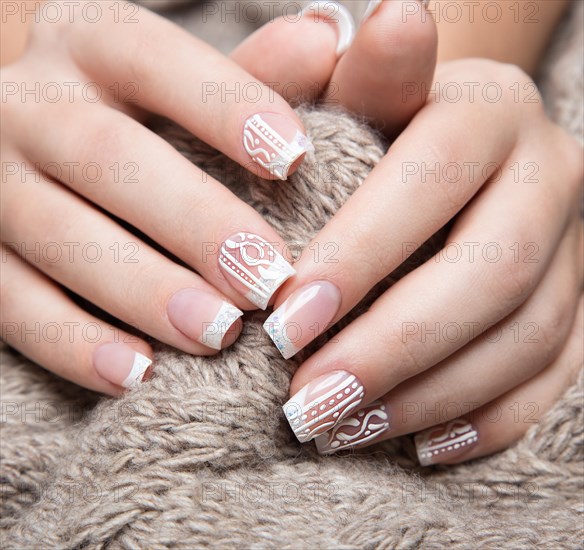 Snow White manicure on female hands. Winter nail design. Picture taken in the studio on a background of wool