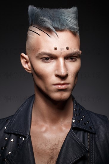 Young man with blue hair and creative makeup and hair. Photo taken in the studio