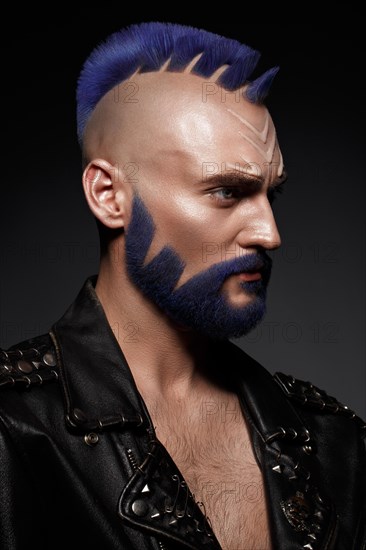 Young man with blue hair and creative makeup and hair. Photo taken in the studio