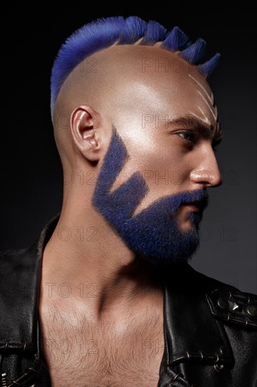 Young man with blue hair and creative makeup and hair. Photo taken in the studio