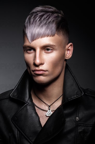 Young man with purple hair and creative makeup and hair. Photo taken in the studio