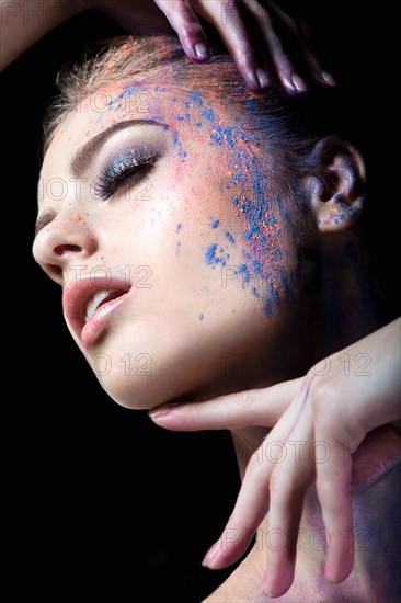 Portrait of a beautiful Girl with red paint on her face. Photo shot in the Studio on a black background