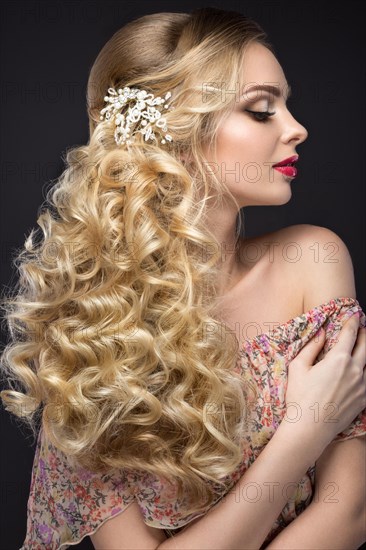 Portrait of a beautiful blond girl in image of the bride with purple flowers on her head. Beauty face. Photo shot in the Studio on a grey background