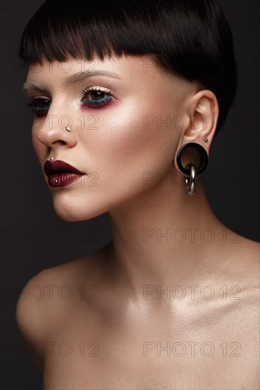 A beautiful girl with art creative make-up and earrings on the face. Photos shot in studio