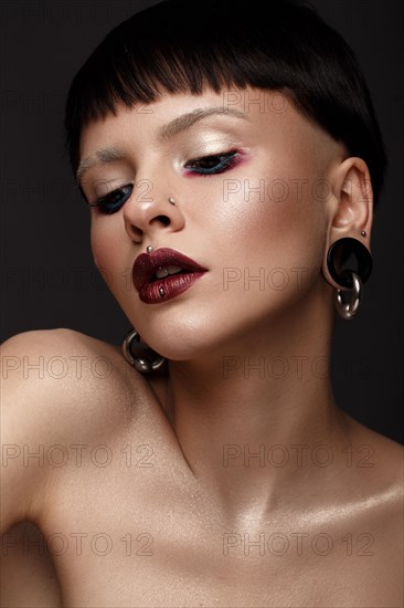 A beautiful girl with art creative make-up and earrings on the face. Photos shot in studio