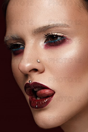 A beautiful girl with art creative make-up and earrings on the face. Photos shot in studio