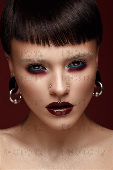 A beautiful girl with art creative make-up and earrings on the face. Photos shot in studio
