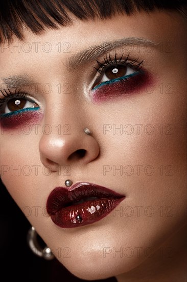 A beautiful girl with art creative make-up and earrings on the face. Photos shot in studio
