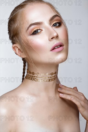 Beautiful girl with a golden shiny make-up and a haircut on her head. Beauty face. Photo taken in the studio