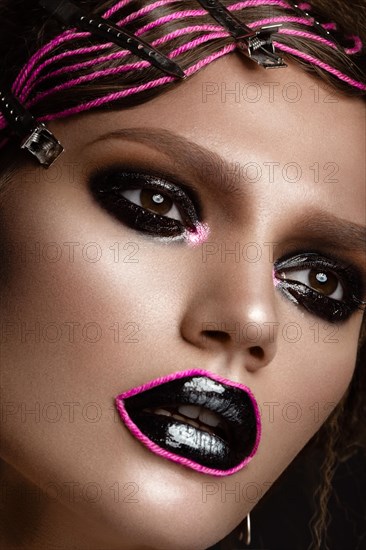 A beautiful girl with a black creative make-up and a pink thread on her lips. Beauty face. Photos shot in studio