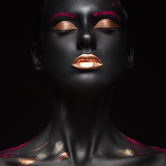 Fashion portrait of a dark-skinned girl with color make-up.Beauty face. Picture taken in the studio on a black background