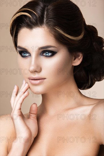 Beautiful brunette girl with evening make-up and perfect skin. Beauty face. Picture taken in the studio on a gray background