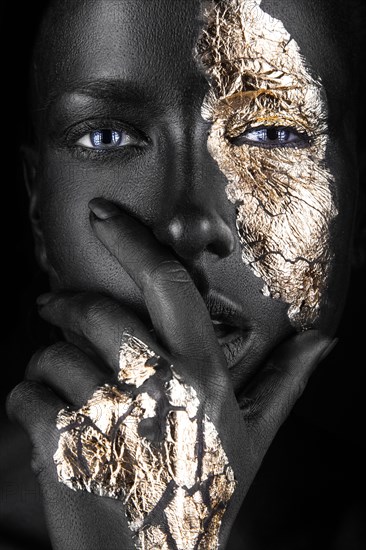 Fashion portrait of a dark-skinned girl with gold make-up.Beauty face. Picture taken in the studio on a black background