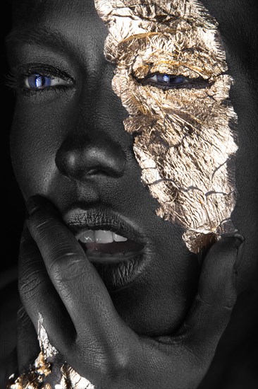 Fashion portrait of a dark-skinned girl with gold make-up.Beauty face. Picture taken in the studio on a black background