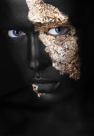 Fashion portrait of a dark-skinned girl with gold make-up.Beauty face. Picture taken in the studio on a black background