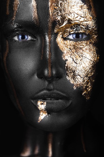 Fashion portrait of a dark-skinned girl with gold make-up.Beauty face. Picture taken in the studio on a black background