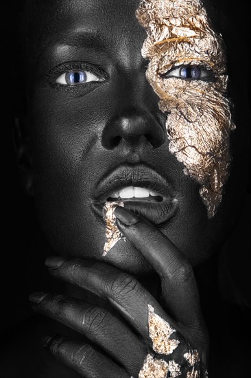 Fashion portrait of a dark-skinned girl with gold make-up.Beauty face. Picture taken in the studio on a black background