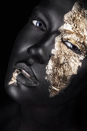 Fashion portrait of a dark-skinned girl with gold make-up.Beauty face. Picture taken in the studio on a black background