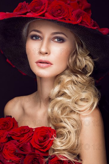 Beautiful blond girl in a dress and hat with roses