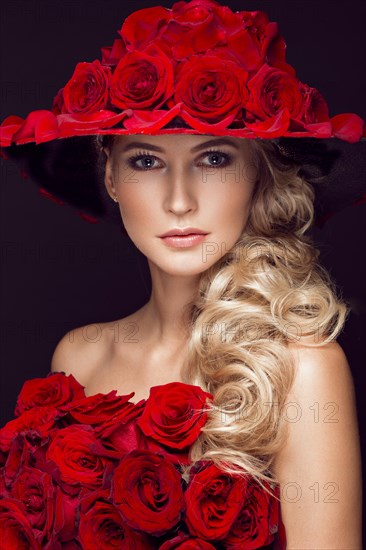 Beautiful blond girl in a dress and hat with roses