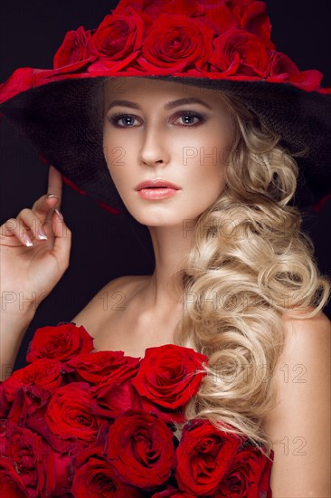 Beautiful blond girl in a dress and hat with roses