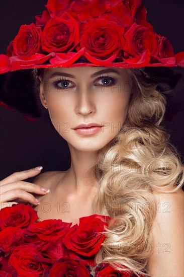 Beautiful blond girl in a dress and hat with roses