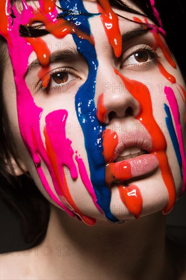 Portrait of a beautiful Girl with red paint on her face. Photo shot in the Studio on a black background