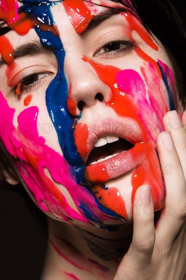 Portrait of a beautiful Girl with red paint on her face. Photo shot in the Studio on a black background