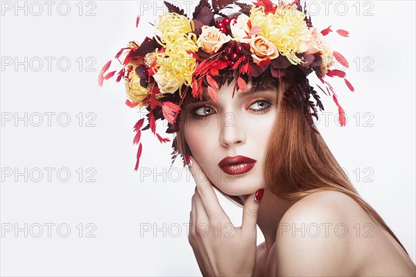 Beautiful girl with bright autumn wreath of leaves and flowers. Beauty face. Picture taken in the studio on a white background