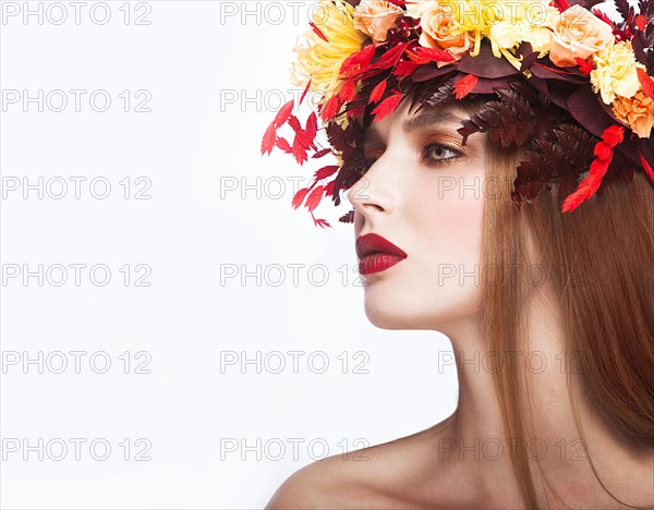 Beautiful girl with bright autumn wreath of leaves and flowers. Beauty face. Picture taken in the studio on a white background