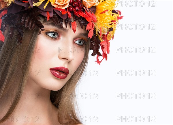 Beautiful girl with bright autumn wreath of leaves and flowers. Beauty face. Picture taken in the studio on a white background