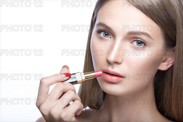 Beautiful young girl with a light natural make-up and beauty tools in hand. Picture taken in the studio on a white background