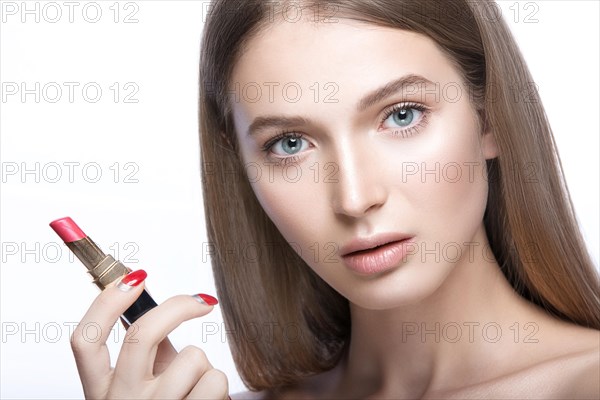 Beautiful young girl with a light natural make-up and beauty tools in hand. Picture taken in the studio on a white background