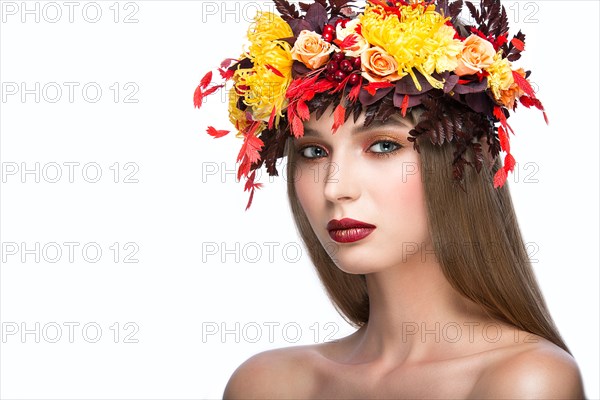 Beautiful girl with bright autumn wreath of leaves and flowers. Beauty face. Picture taken in the studio on a white background