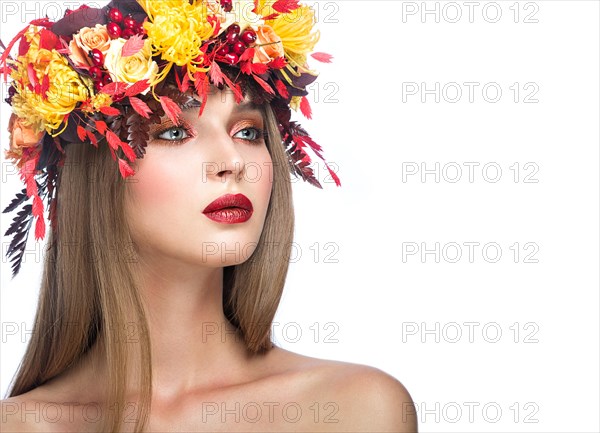 Beautiful girl with bright autumn wreath of leaves and flowers. Beauty face. Picture taken in the studio on a white background