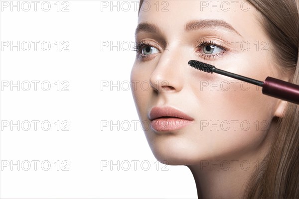 Beautiful young girl with a light natural make-up and beauty tools in hand. Picture taken in the studio on a white background